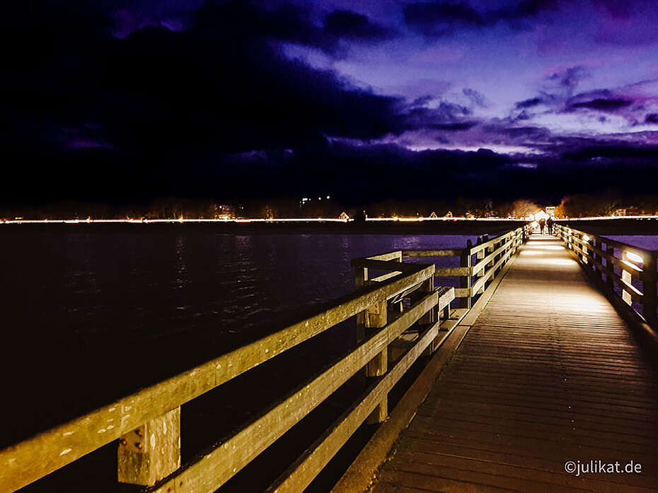 Beleuchtete Seebrücke vor violetten Himmel