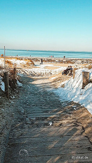 Strandaufgang zwischen verschneiten Dünen