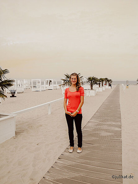 Autorin auf dem Holzsteg vor karibischer Strandbar mit Palmen